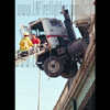 photograph of a truck hanging off a bridge